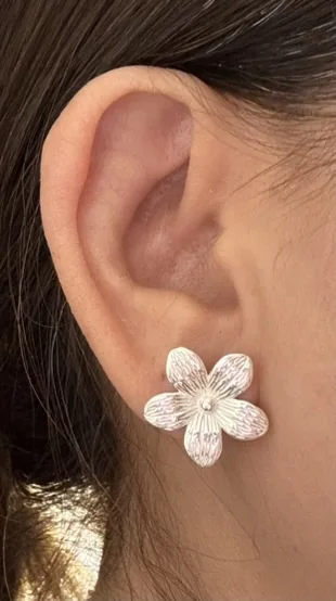 Arete floral llevado en la oreja